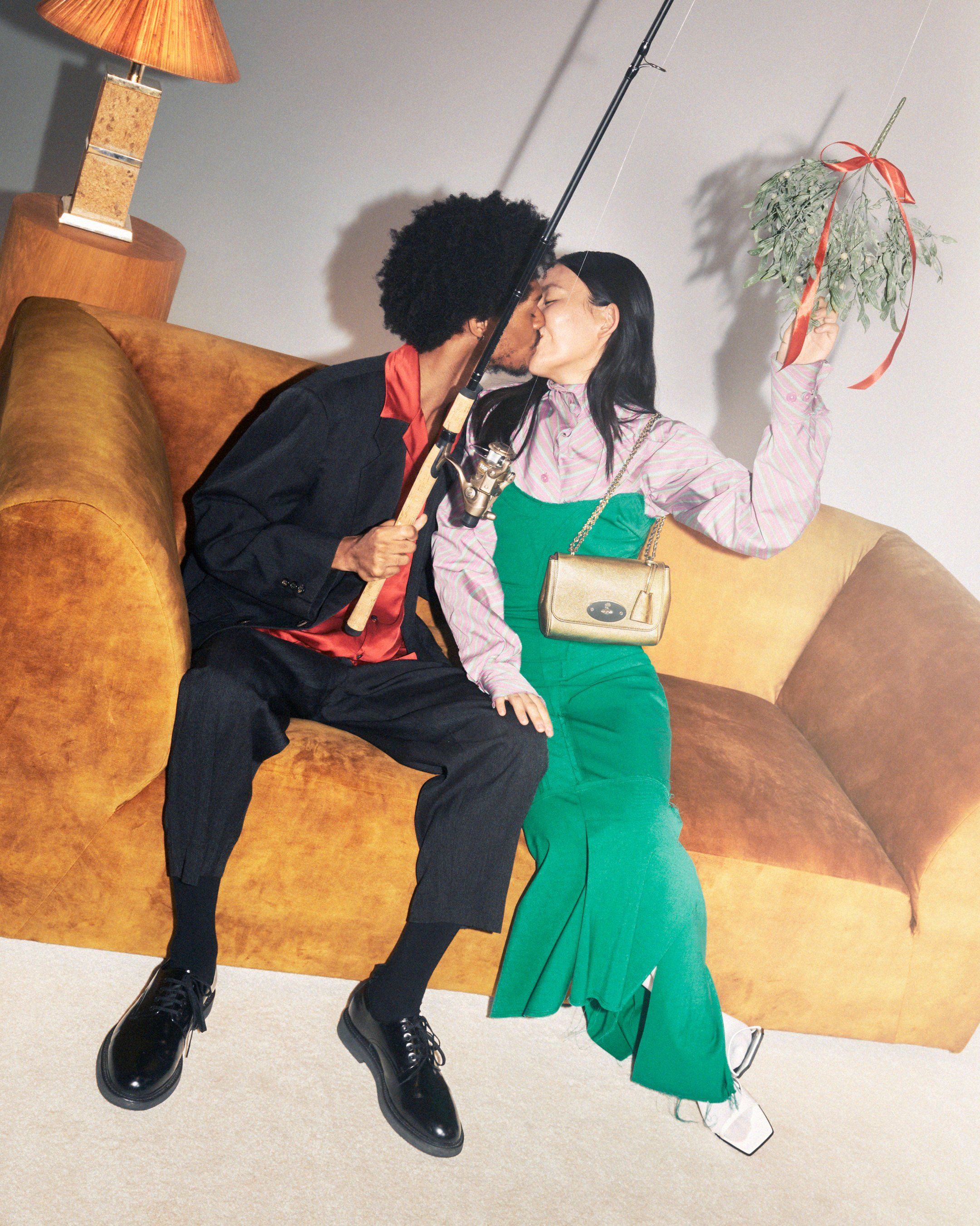 Zwei Models küssen sich unter dem Mistelzweig mit der Lily-Tasche aus goldenem Leder